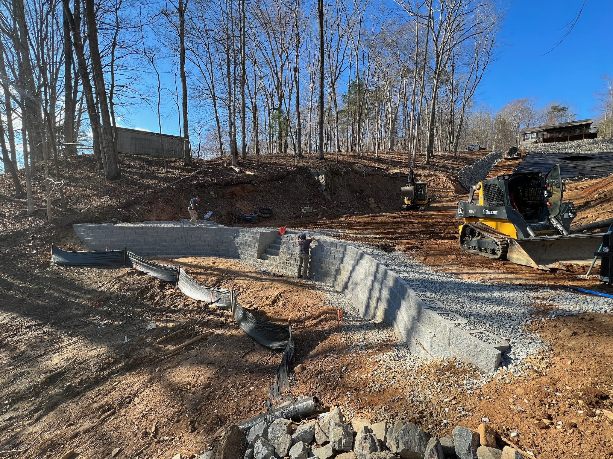 Ridgestone crew building a retaining wall with equipment on site