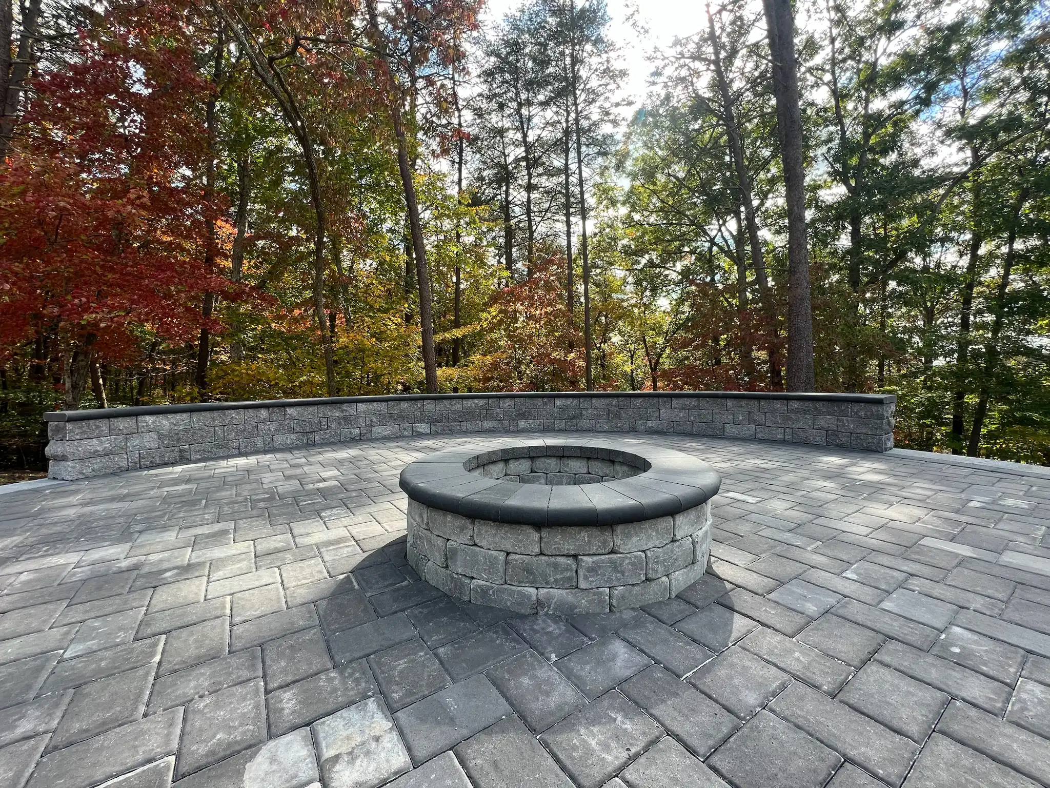 Large circular paver patio with sitting wall in natural setting